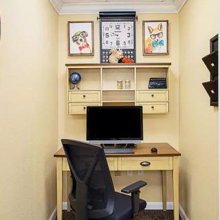 A compact home office setup featuring a desk, computer, and decorative wall art.