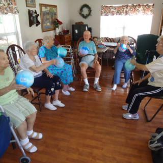 A group of seniors participating in a seated ball game indoors.