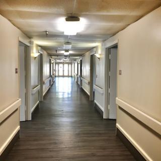 A long, well-lit hallway with doors on either side.