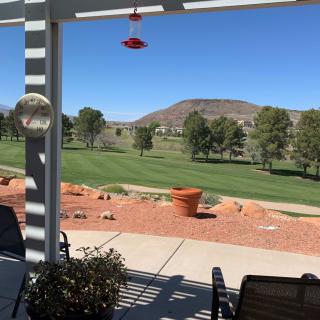 A scenic view from a patio overlooking a golf course with mountains in the background.