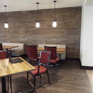 A cozy dining area featuring modern chairs and tables, with warm lighting against a textured wall.