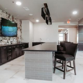 A modern kitchen interior featuring an island counter with seating and a wall-mounted television.