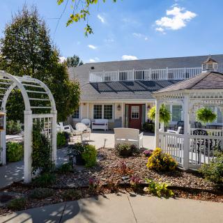 A beautifully landscaped outdoor area featuring a gazebo and archway under a sunny sky.
