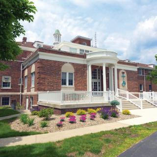 A brick building with columns at the entrance and landscaped surroundings.