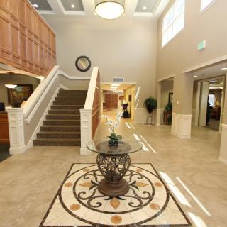 A spacious and elegantly designed lobby with a central decorative table and staircase.