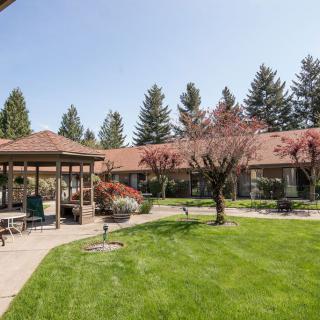 A serene outdoor garden with a gazebo and lush green lawn.