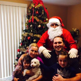 A family posing with Santa Claus in front of a decorated Christmas tree.