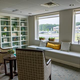 A cozy lounge area with a window seat, bookshelves, and comfortable seating.