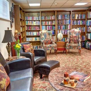 A cozy library reading area with comfortable chairs and bookshelves filled with books.