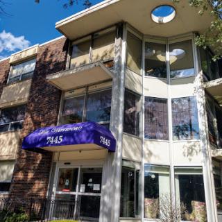 A modern apartment building featuring large windows and a purple canopy.