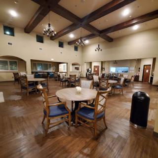A spacious and cozy dining area featuring elegant wooden furniture and chandeliers.