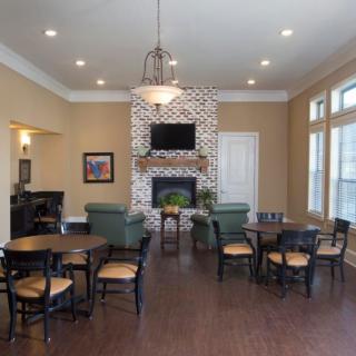 A modern community room with a fireplace, television, and seating area.