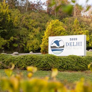 A welcoming sign for Delhi surrounded by lush greenery.
