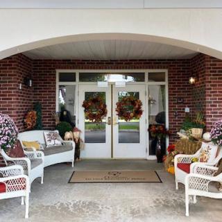 A welcoming front porch decorated for fall with wreaths and cozy seating.