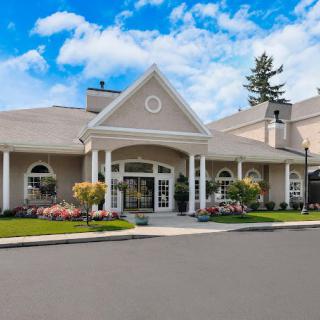 A large building with a grand entrance and well-maintained landscaping under a partially cloudy sky.