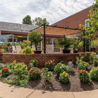A beautifully landscaped garden with a patio and pergola surrounded by vibrant flowers.