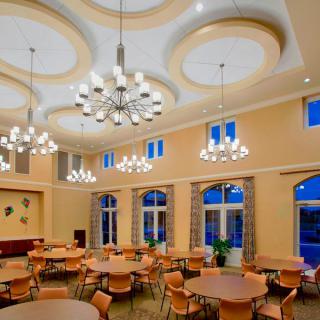 Elegant dining hall with round tables, chairs, and chandeliers.