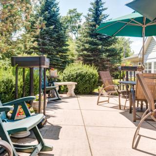 A sunny patio with outdoor seating and umbrellas surrounded by lush greenery.