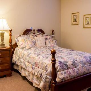 A cozy bedroom with a floral-patterned bedspread and a bedside lamp.
