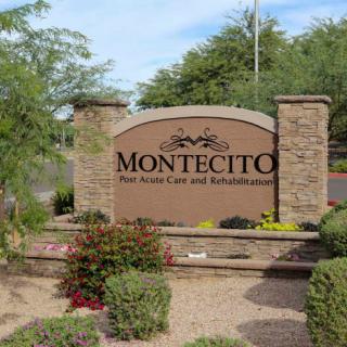 Entrance sign for Montecito, surrounded by plants and stone pillars.