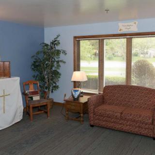 A cozy living room with a sofa, lamp, and wooden furniture near large windows.