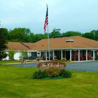 A building with an American flag flying outside, surrounded by grass and trees.