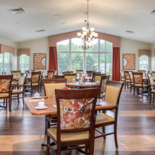 A spacious and elegantly designed dining room featuring multiple tables and chairs, with large windows allowing natural light to fill the space.