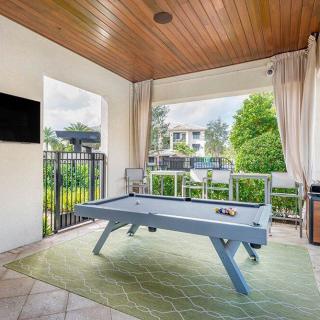 An outdoor recreation space featuring a pool table, television, and a garden view.