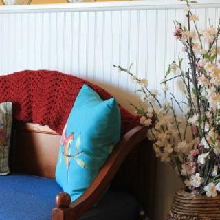 Cozy seating area with a vibrant pillow and floral decor.