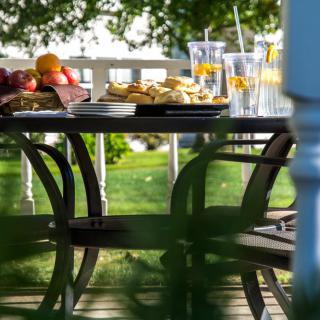 An inviting outdoor table set with food and drinks, surrounded by a lush garden.