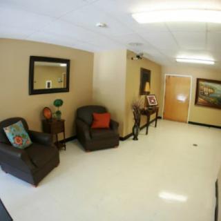 A cozy waiting room with chairs and decorative elements such as mirrors and paintings.