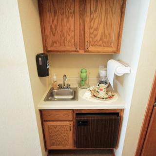 A compact kitchenette with a sink, cabinets, and a mini fridge.