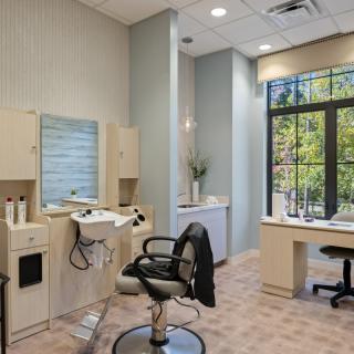 A modern hair salon interior with styling chair and large window.