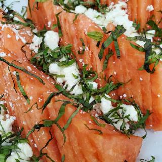 A refreshing watermelon salad topped with feta cheese and fresh herbs.