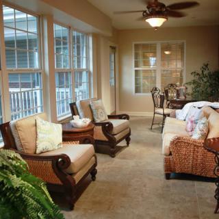 A cozy sunroom with comfortable seating and large windows, allowing natural light to fill the space.