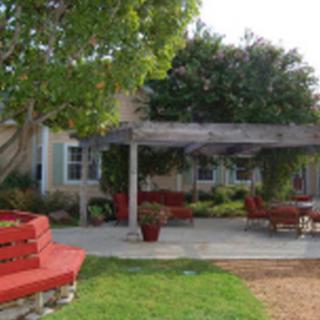An inviting outdoor patio with a pergola and comfortable seating surrounded by lush greenery.