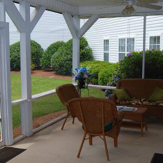 A cozy covered porch with wicker chairs and a garden view.