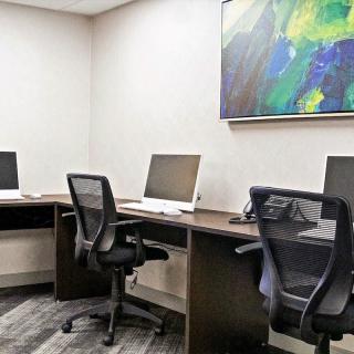 A modern office space with multiple workstations and abstract artwork on the wall.