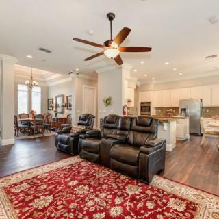 Spacious open living area with leather seating, a ceiling fan, and an adjoining kitchen and dining space.