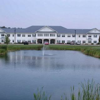 A serene view of a residential building by a tranquil pond.