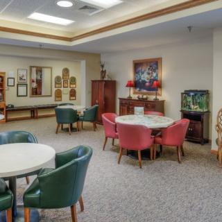 A cozy lounge area featuring tables with colorful chairs, an aquarium, and various artwork on the walls.