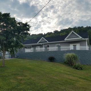 A modern house set against a scenic landscape with lush green grass and cloudy skies.