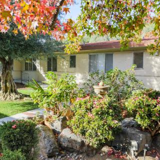 A charming house surrounded by vibrant autumn foliage and a well-maintained garden.