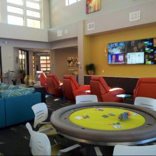 A modern lounge area featuring comfortable seating, a gaming table, and a large television.