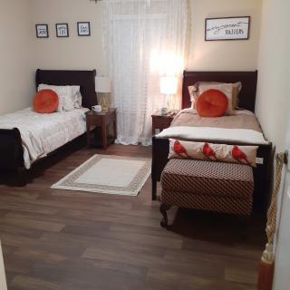 A cozy bedroom with two neatly made single beds, decorated with orange pillows and artwork on the walls.
