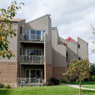 A modern apartment building with multiple balconies and surrounding greenery.