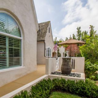 A beautifully landscaped garden area with a patio and decorative vase next to a house.