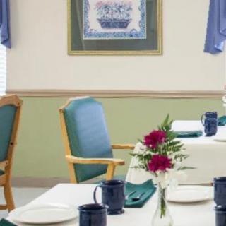 A neatly set dining room table with chairs, adorned with a bouquet of flowers.