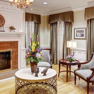 A beautifully decorated living room with a fireplace, elegant furniture, and a floral centerpiece.