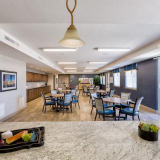 A modern dining space with multiple tables and chairs, complemented by contemporary lighting and kitchen facilities.